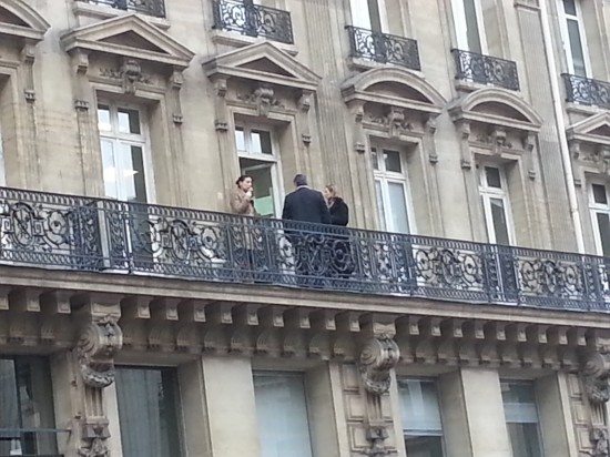 Smoking on the balcony of an office building, with the doors open so the smoke wafts in.